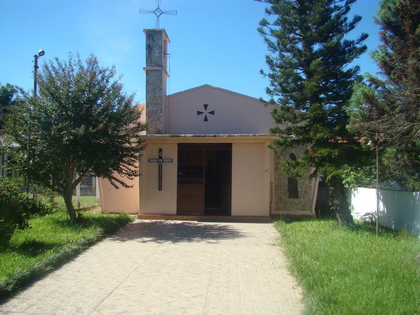 Fachada da Igreja Santa Teresinha, com a torre de pedra e a cruz.